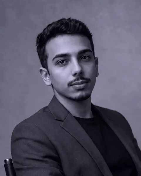 Portrait of Salvador Torrez: seated, in a dark blazer, against a grey background.