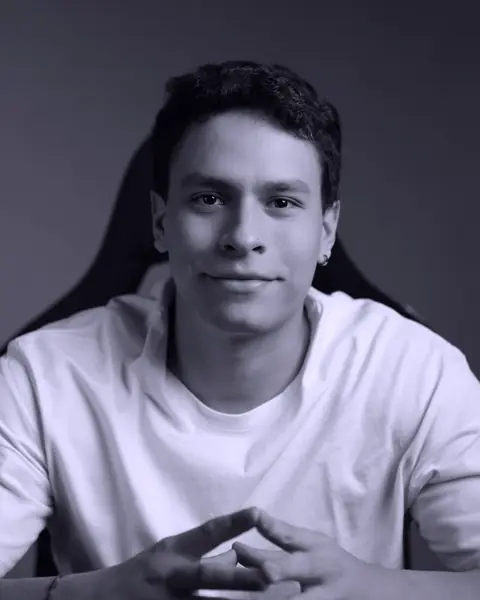 Portrait of Santiago Guillén: seated, in a light T-shirt, with his hands together.